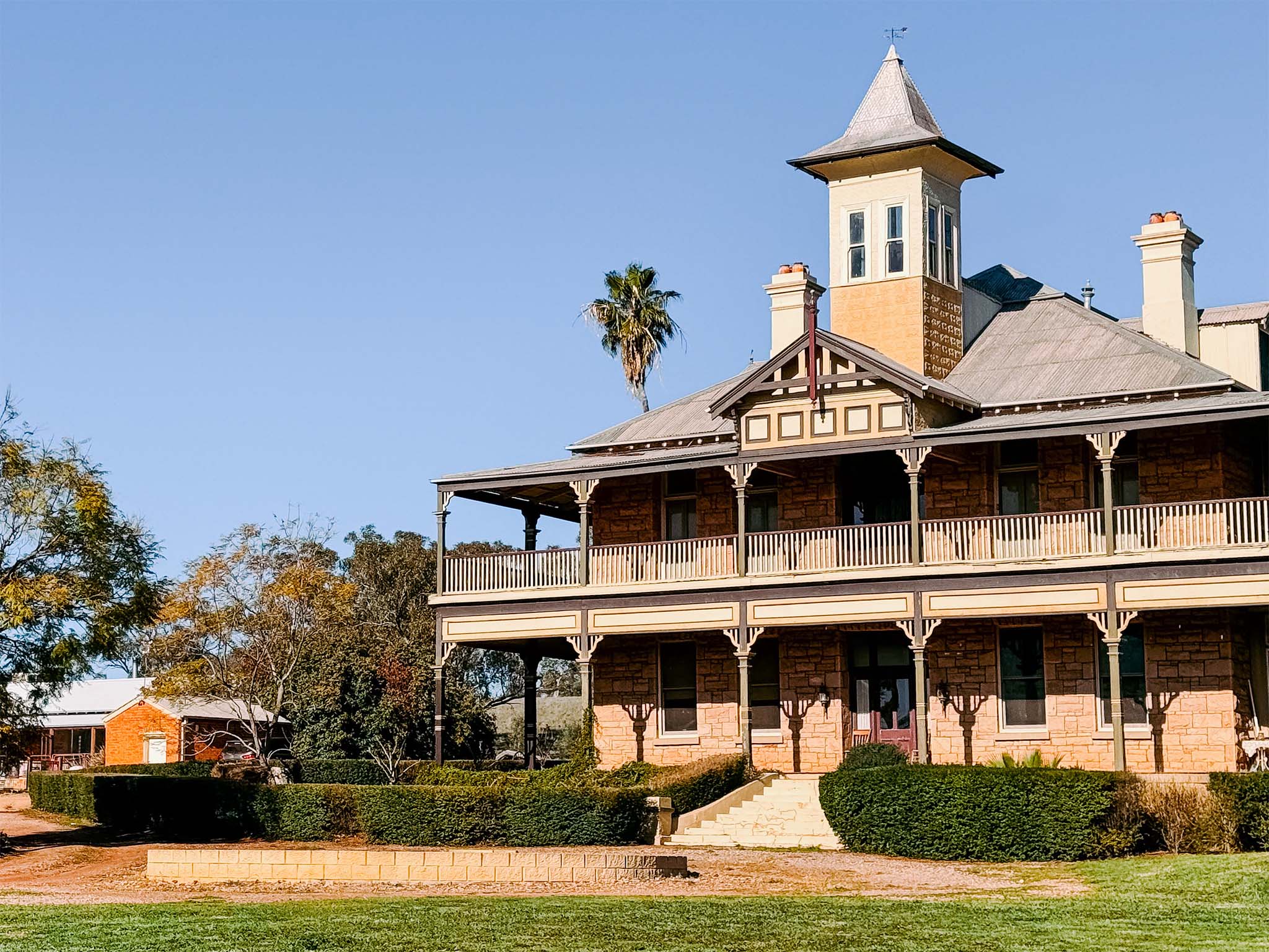 The historic Merribee Station homestead with wraparound verandas and landscaped gardens.
